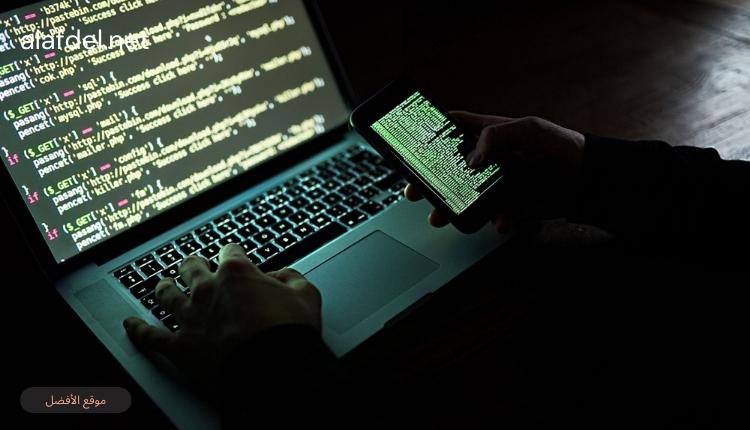 صورة بها شخص يمسك هاتف وأمامه لاب توب ضمن الحديث عن Dark Web أو الإنترنت المظلم