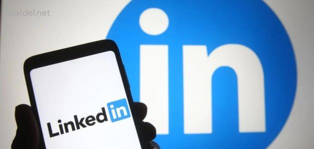 صورة بها يد تمسك هاتف ذكي مكتوب على شاشته LinkedIn وخلفه شعار LinkedIn ضمن الحديث عن ما هو لينكد إن