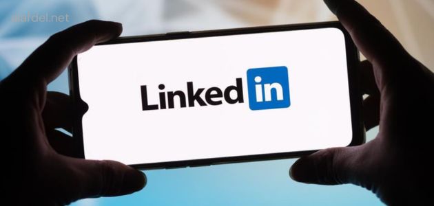 صورة بها يد شخص تمسك هاتف ذكي مكتوب على شاشته LinkedIn ضمن الحديث عن فائدة موقع LinkedIn