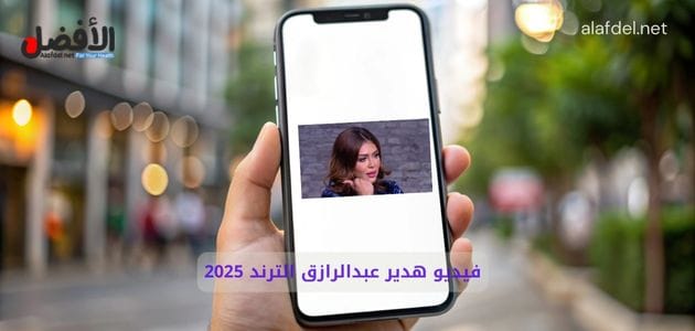 صورة بها يد تمسك بهاتف عليه صورة البلوجر هدير عبد الرازق ضمن الحديث عن فيديو هدير عبدالرازق الترند 2025