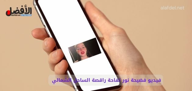 صورة بها يد تمسك هاتف عليه صورة الراقصة نور تفاحه ضمن الحديث عن فيديو فضيحة نور تفاحة راقصة الساحل الشمالي الجريئة